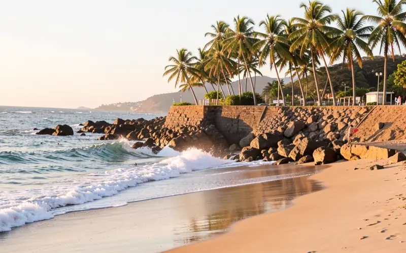 Costa capixaba com coqueiros, pedras e onda quebrando no fim da tarde