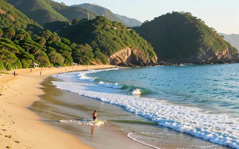 Baía de Imbituba com morros verdes ao redor e linhas de ondas quebrando na areia